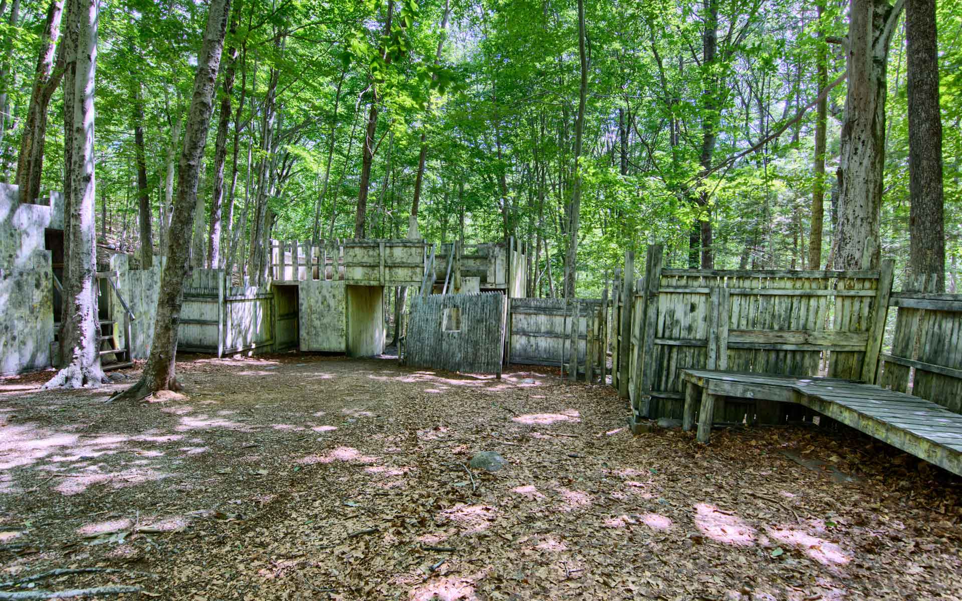 Paintball arena in a wooded area with wooden bunkers and structures.