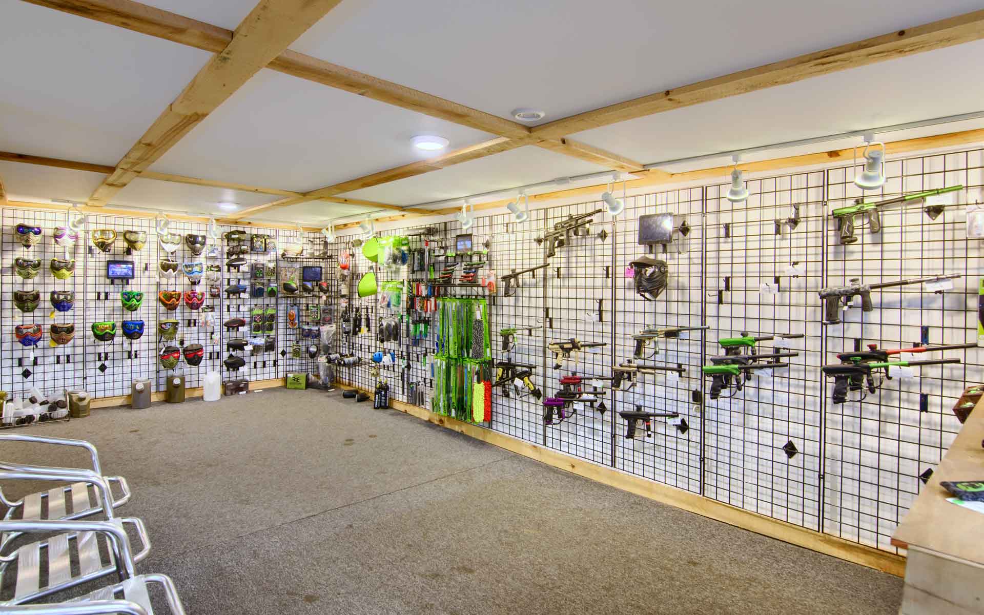 Paintball equipment store interior, guns and gear on display, overhead lighting.