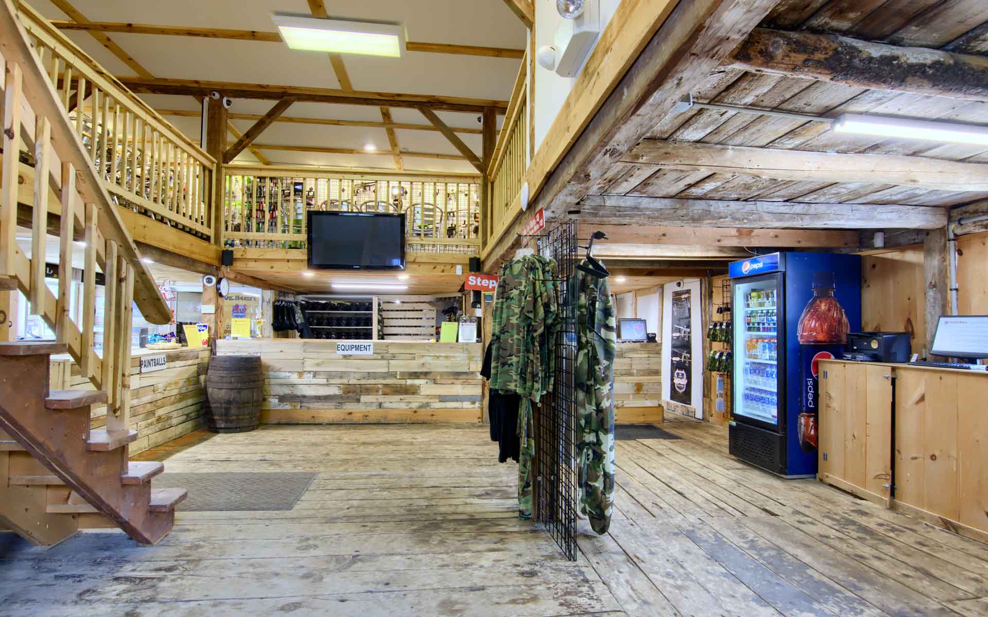 Rustic store interior with wood beams, stairs, merchandise, and a refrigerator.