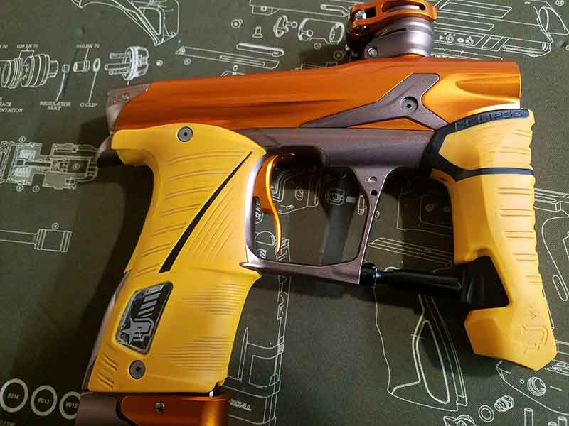 Orange and yellow paintball gun on a green schematic background.