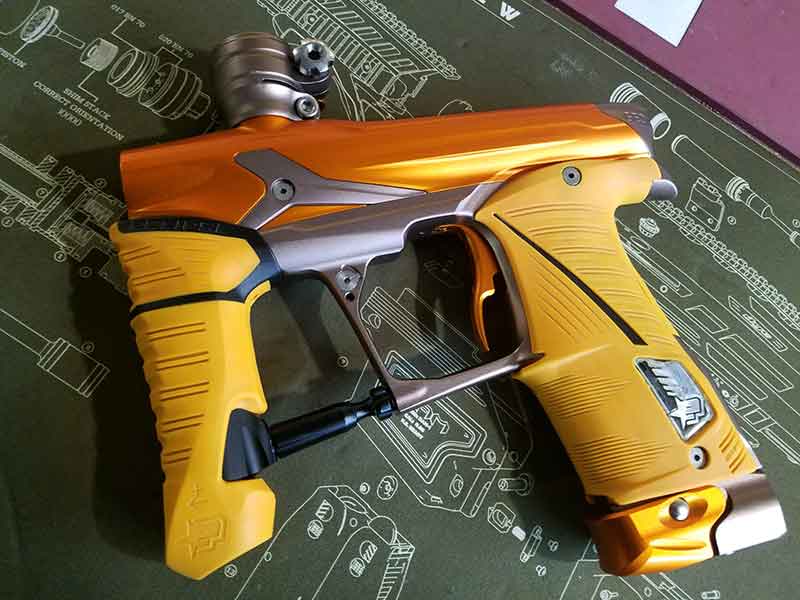 Yellow and gold paintball gun on a green mat with a detailed diagram.
