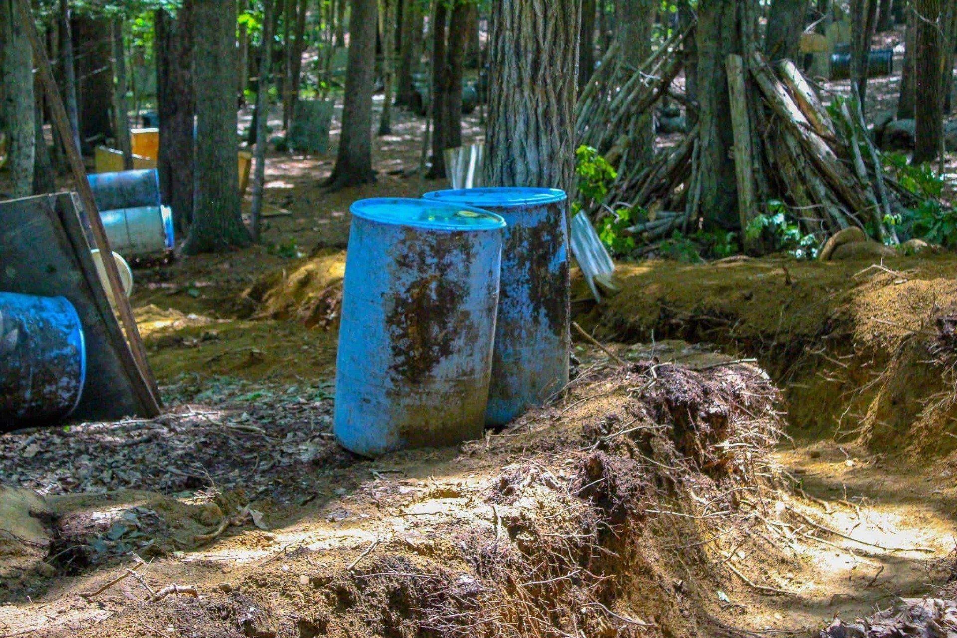 Paintball barrels and trenches in a wooded area, likely for recreational play.