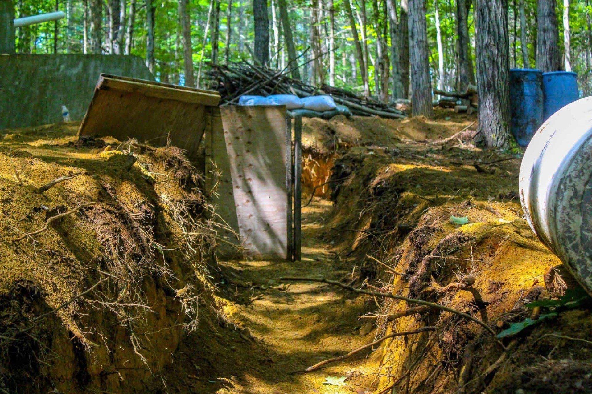 A dugout trench with a wooden door in a wooded area.