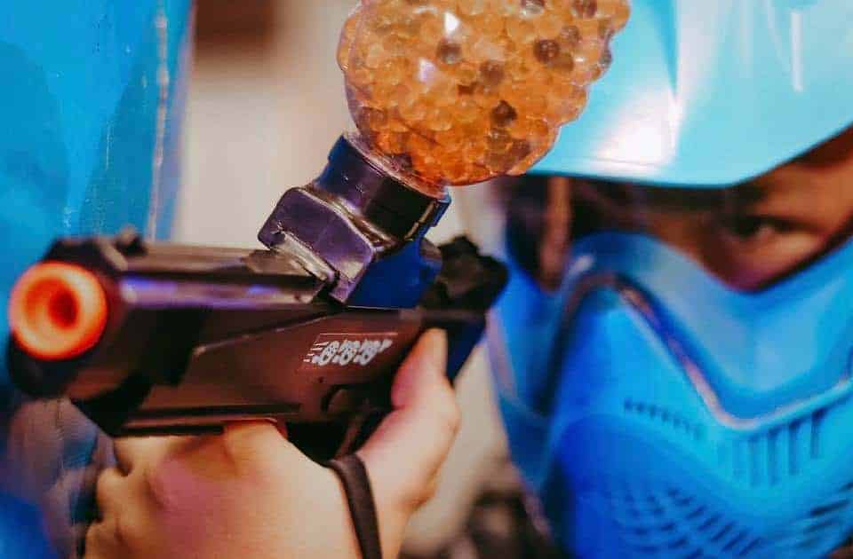 Person in blue safety gear loading water beads into a gel blaster gun.