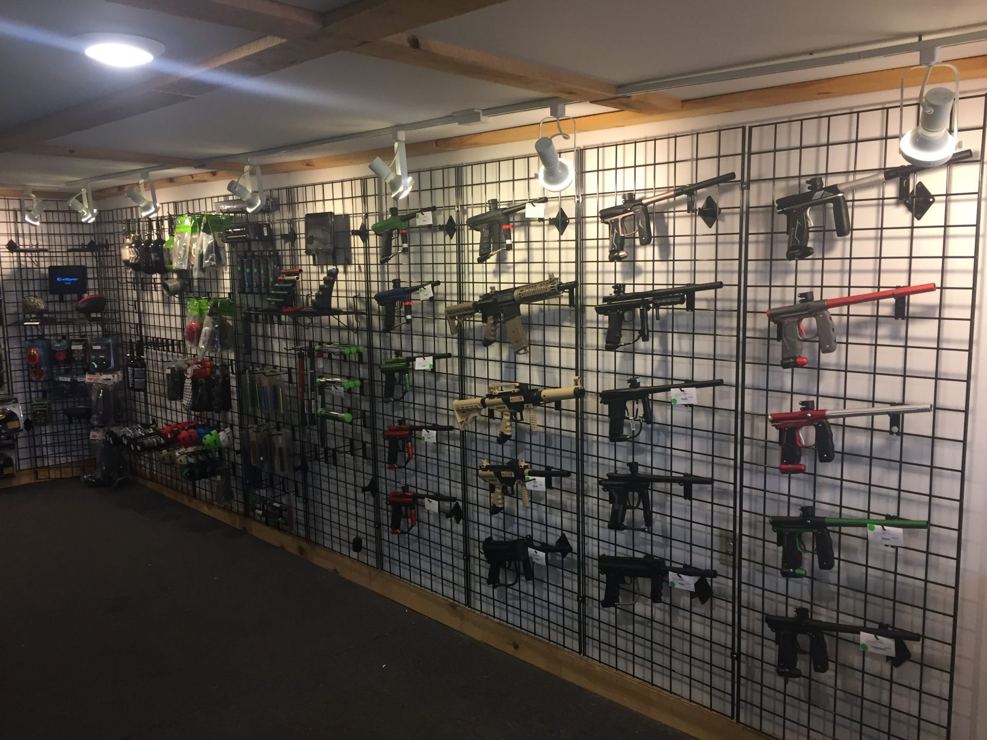 Paintball guns displayed on a grid wall inside a store.