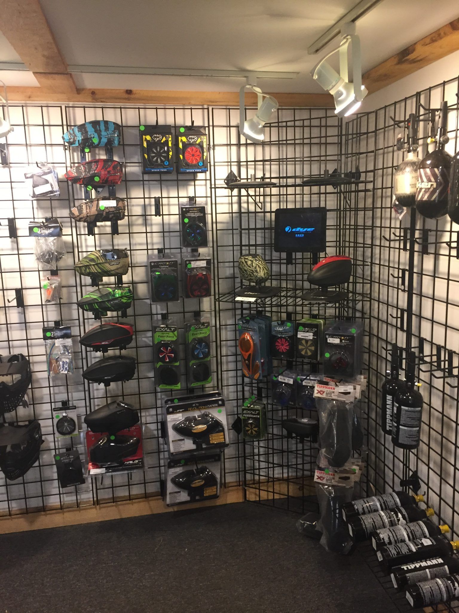 Display of sports equipment, mostly black and camouflage items, on a store wall with a black grid.