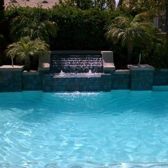 Pool with waterfall, lush greenery, and clear turquoise water.