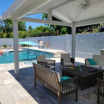Patio with white pergola, pool, and outdoor furniture.