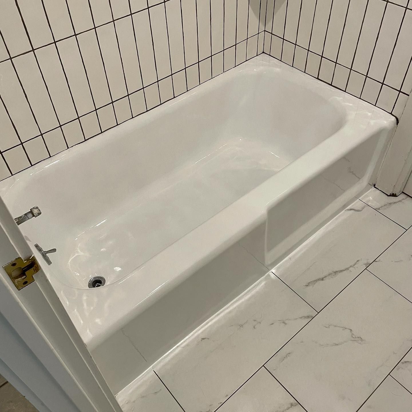 White bathtub in a bathroom with white tile walls and floor.