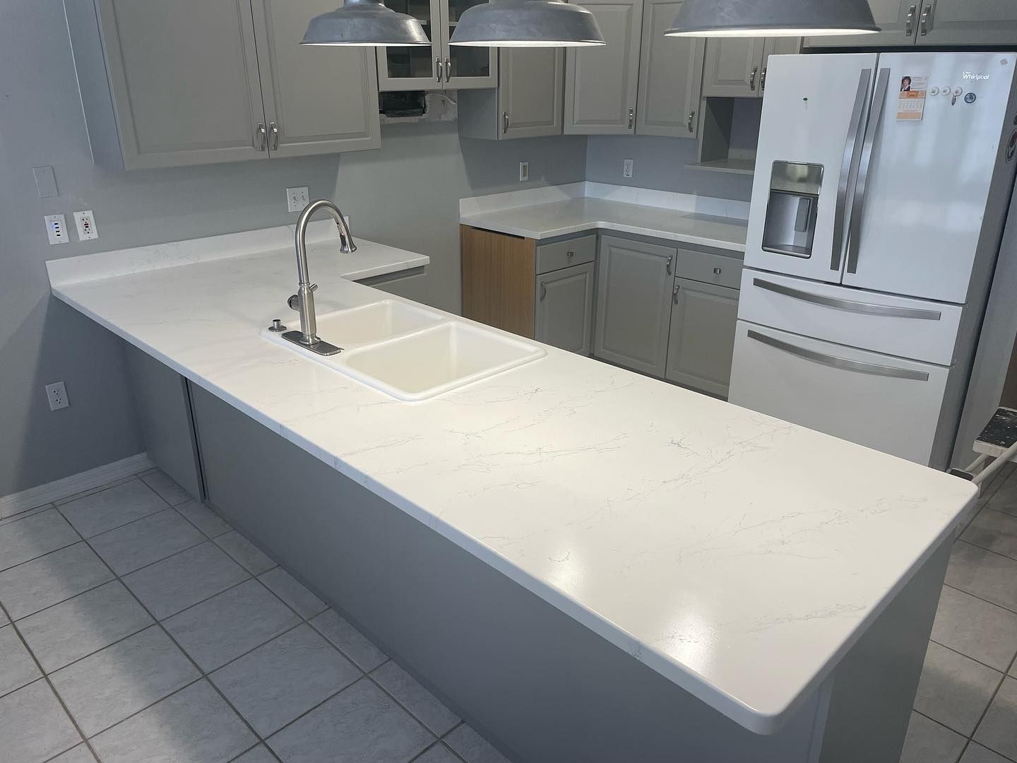 Kitchen with light gray cabinets, white countertops, and stainless steel appliances.