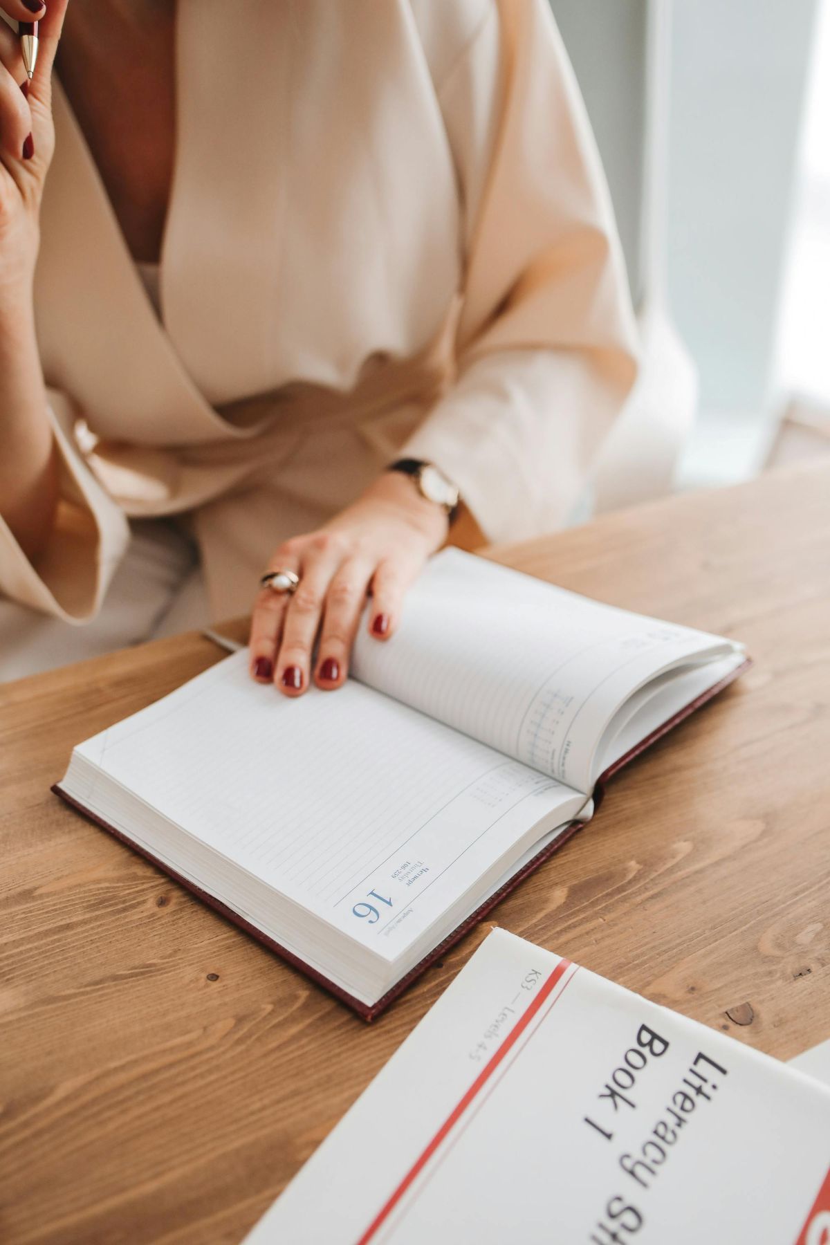 A woman is sitting at a table reading a book.