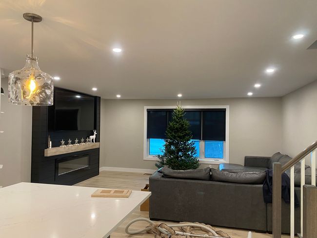 Living room with a Christmas tree, gray sofa, fireplace, and pendant light.