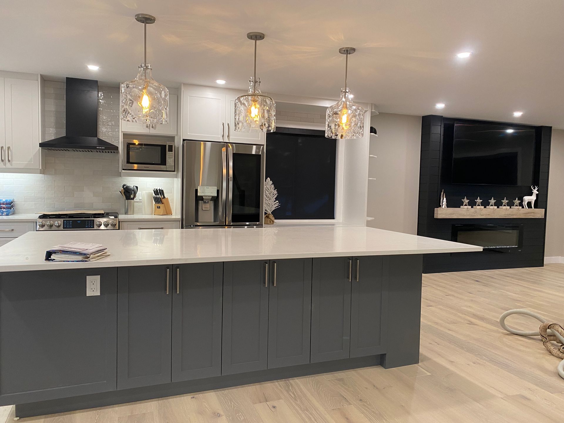 Modern kitchen with a gray island, white cabinets, and three crystal pendant lights.