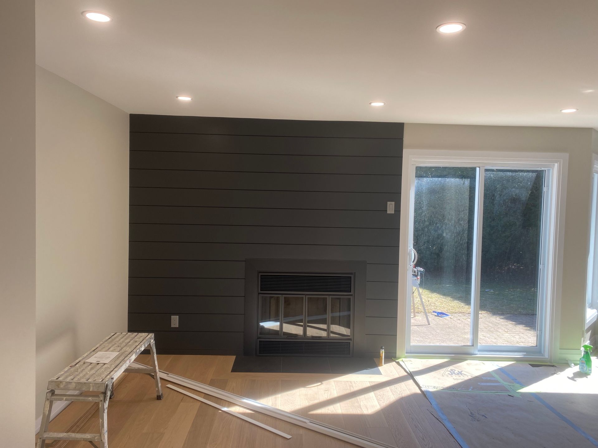 Living room with dark gray accent wall, fireplace, and sliding glass door.