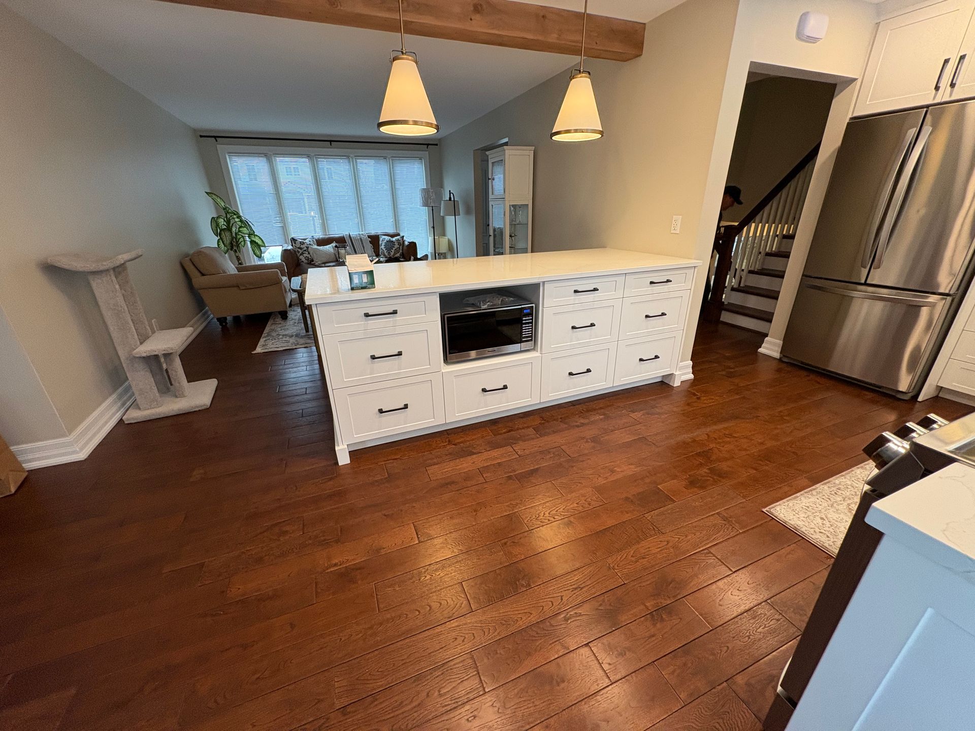 Kitchen with island, hardwood floor, stainless steel fridge, and hanging lights.