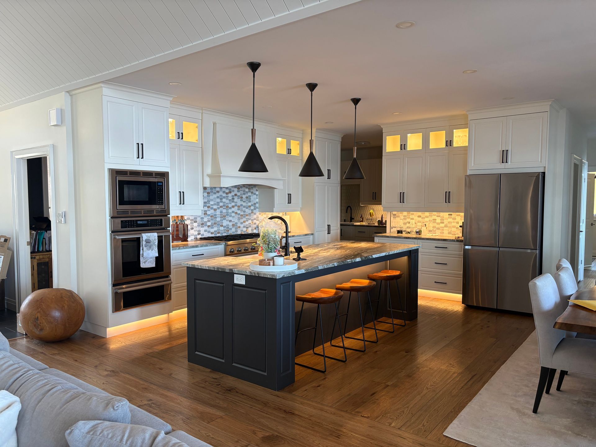 Modern kitchen with a gray island, white cabinets, and pendant lights.