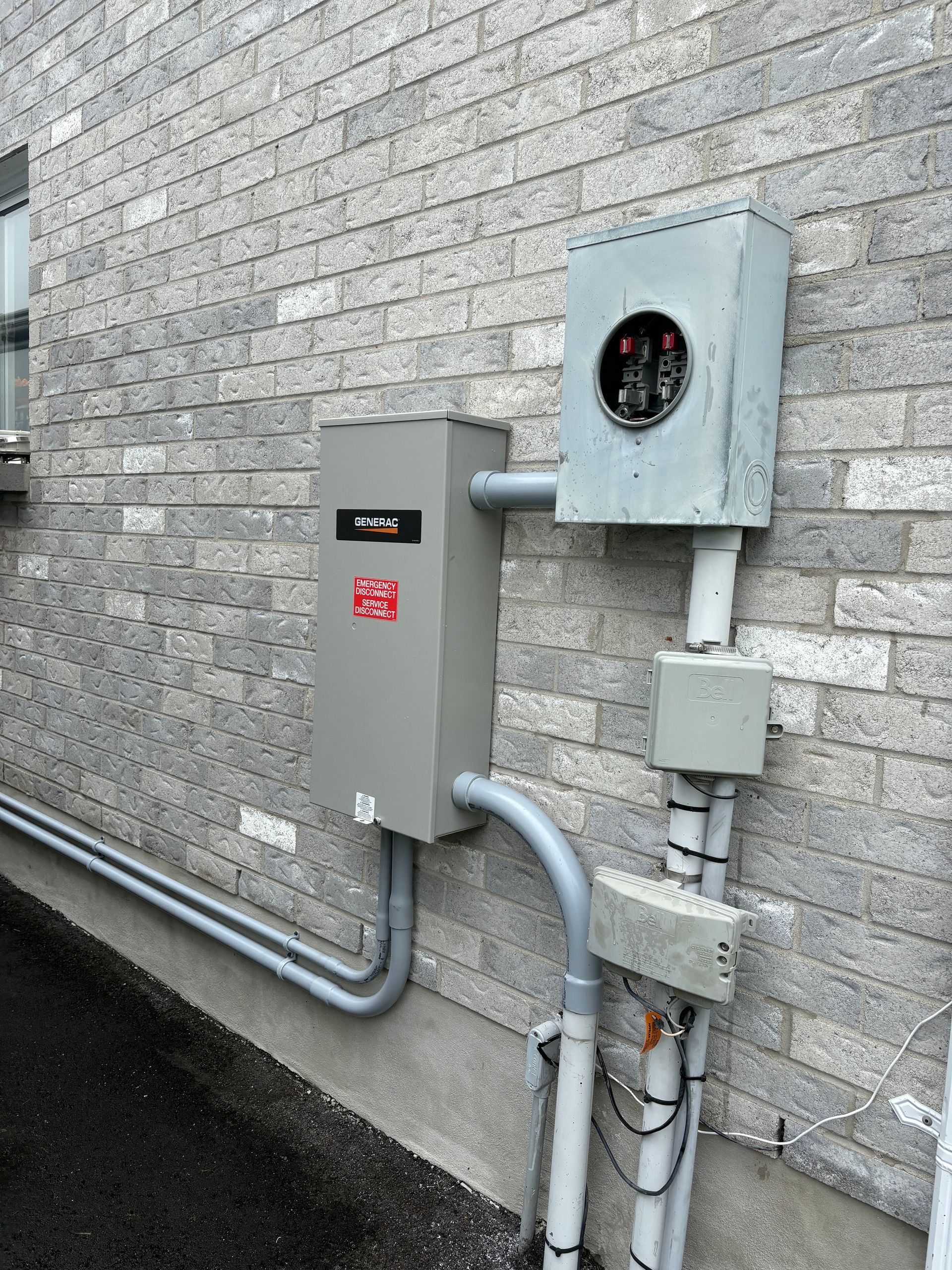 Electrical boxes mounted on a brick wall, including a meter and conduit.