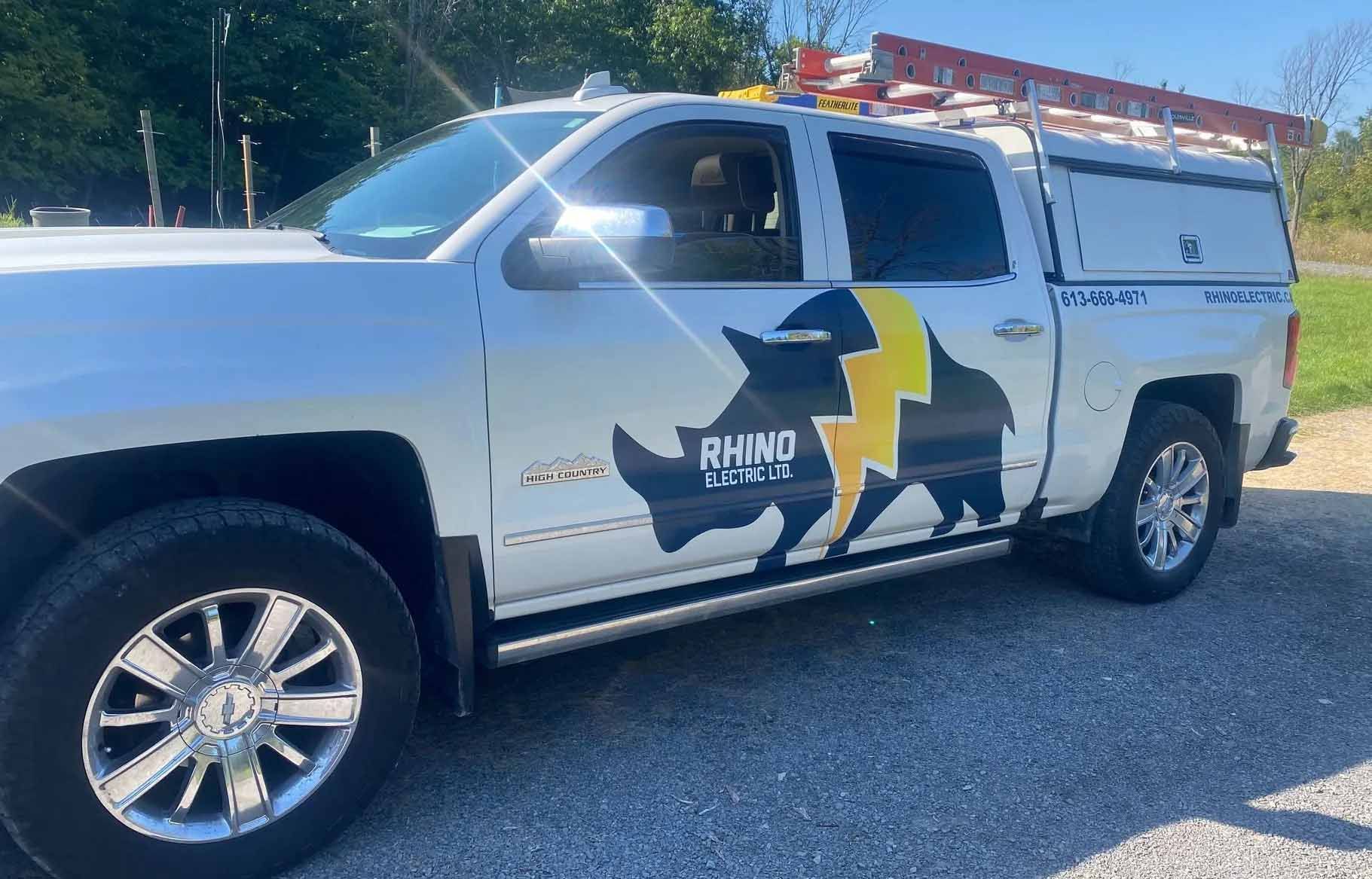 White truck with rhino and lightning bolt logo. Parked outdoors.
