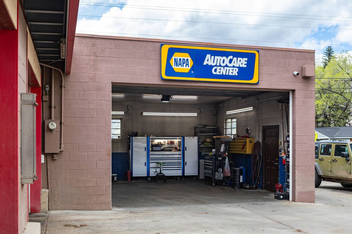 AutoCare Center garage entrance with blue-and-yellow sign and car service equipment inside