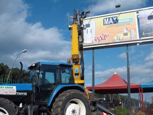 Trattore con gru per servizi di giardinaggio ad alta quota