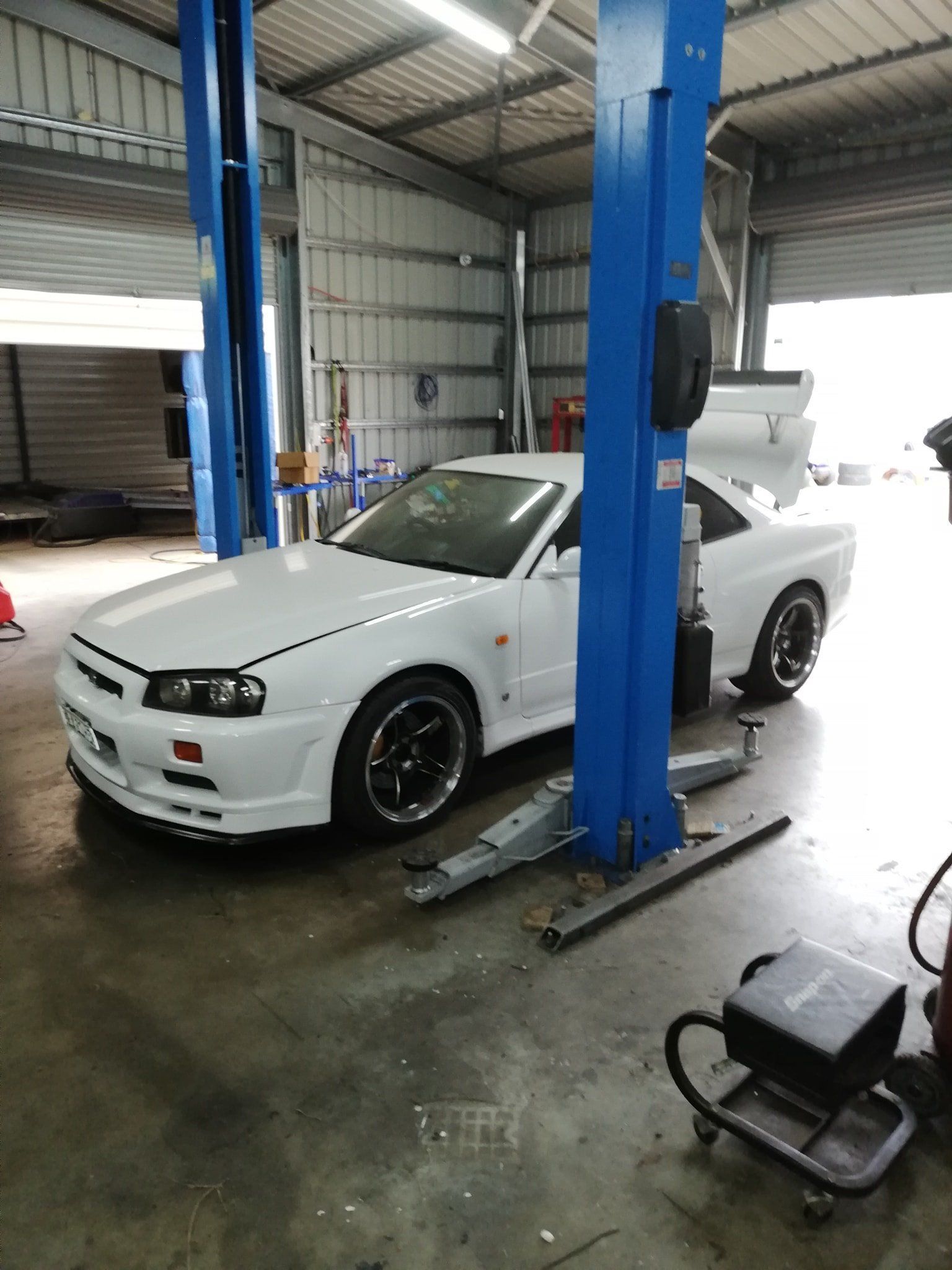 A White Car Is Sitting Between Two Blue Hoists — Dynolink In Garbutt, QLD