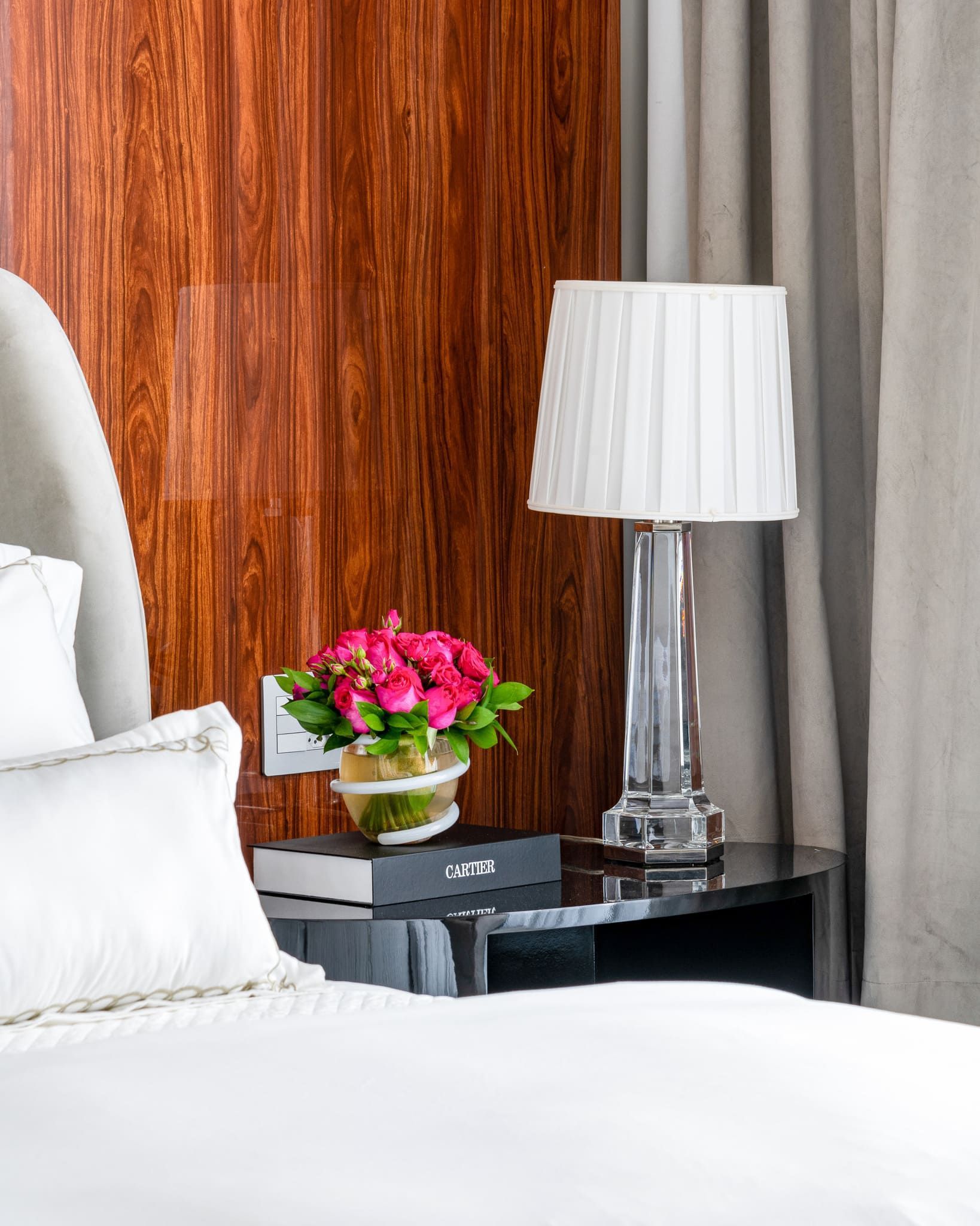 Há um vaso de flores no criado-mudo ao lado da cama.