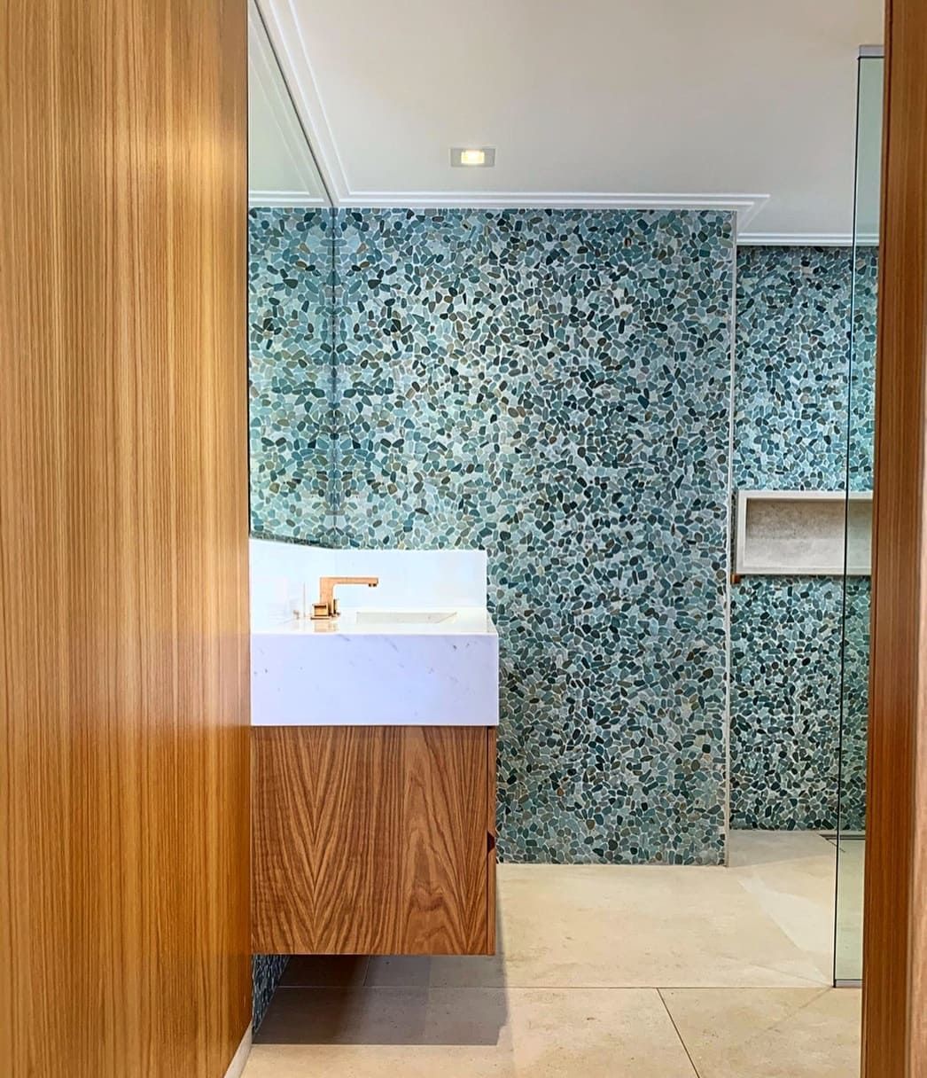 Um banheiro com pia, espelho e azulejos azuis.