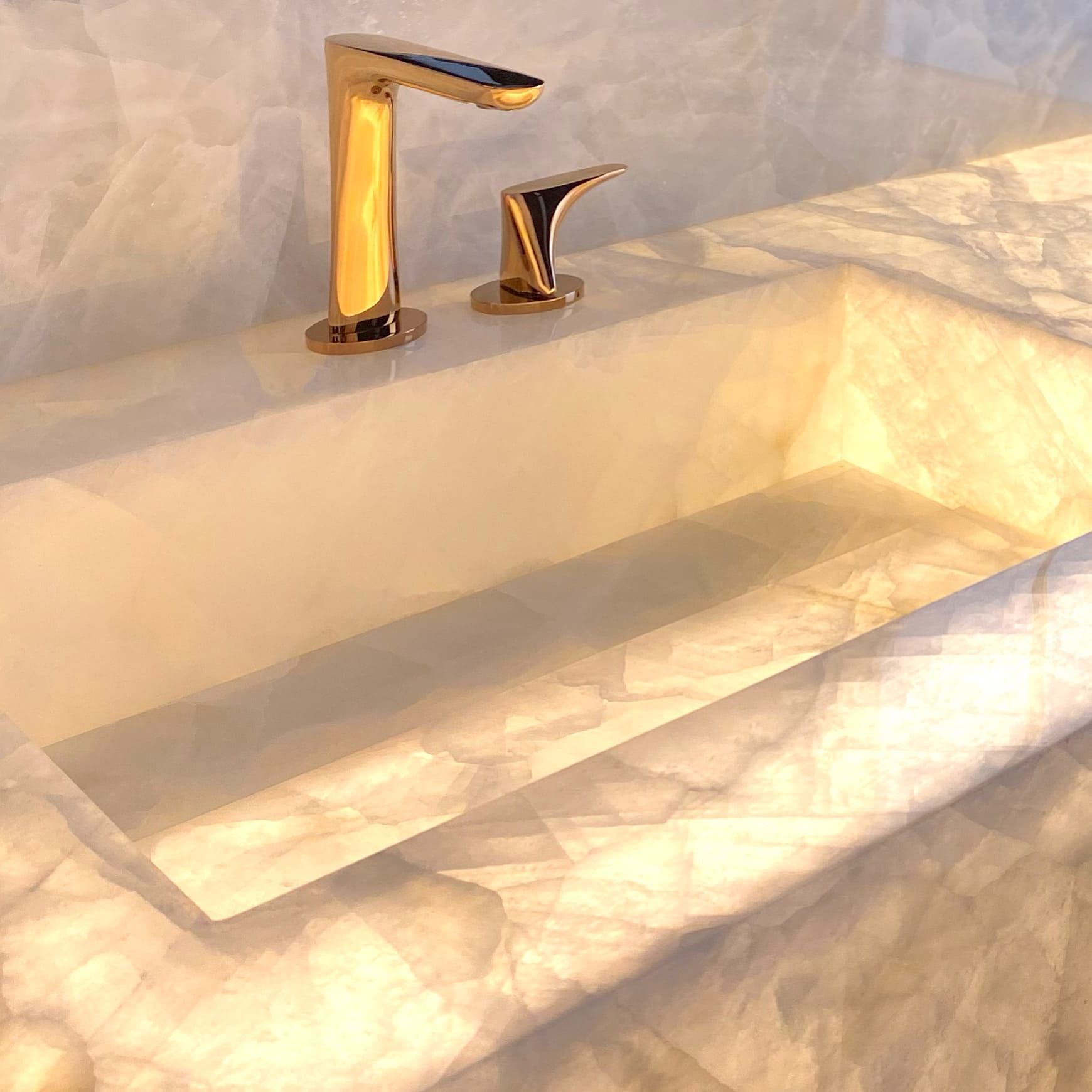 Uma pia de banheiro com uma torneira dourada em cima