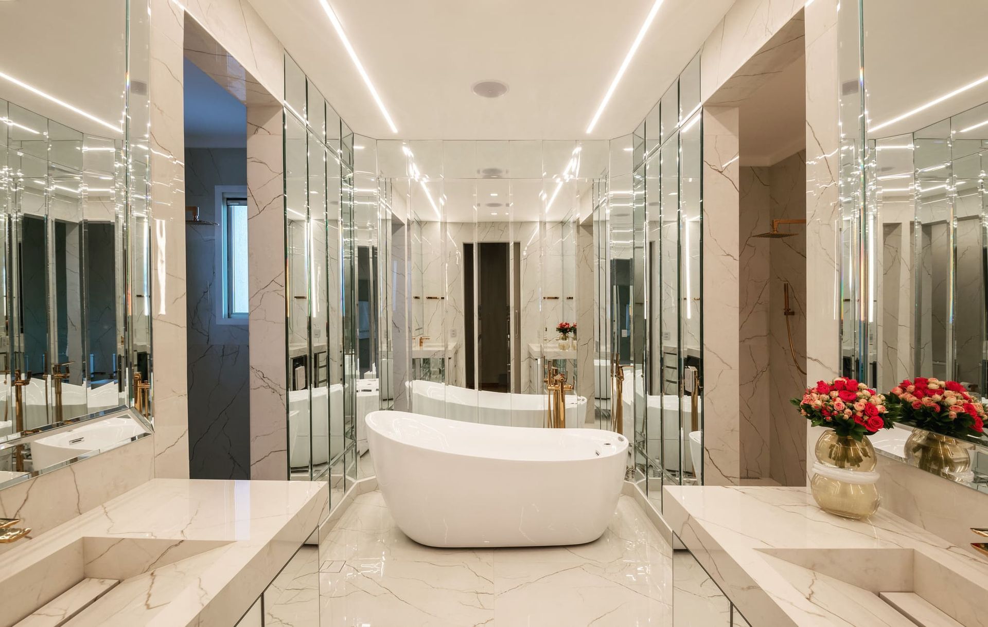 Um banheiro com duas pias, uma banheira e muitos espelhos.