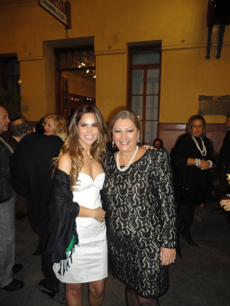 Duas mulheres posando para uma foto em frente a um prédio amarelo
