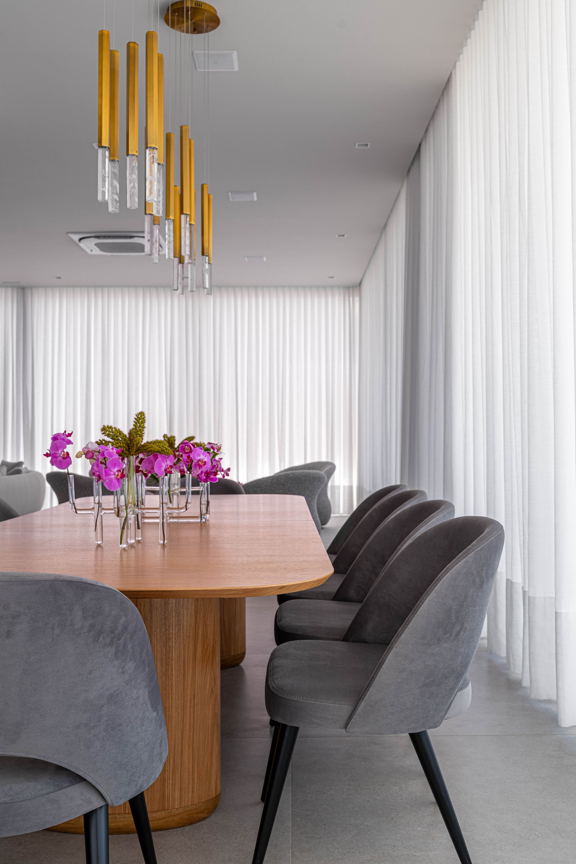Uma sala de jantar com uma mesa e cadeiras e um vaso de flores sobre a mesa.
