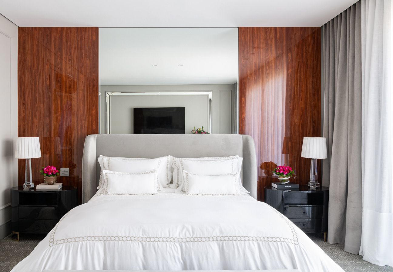 Um quarto com uma cama, mesas de cabeceira, abajures e um espelho grande.