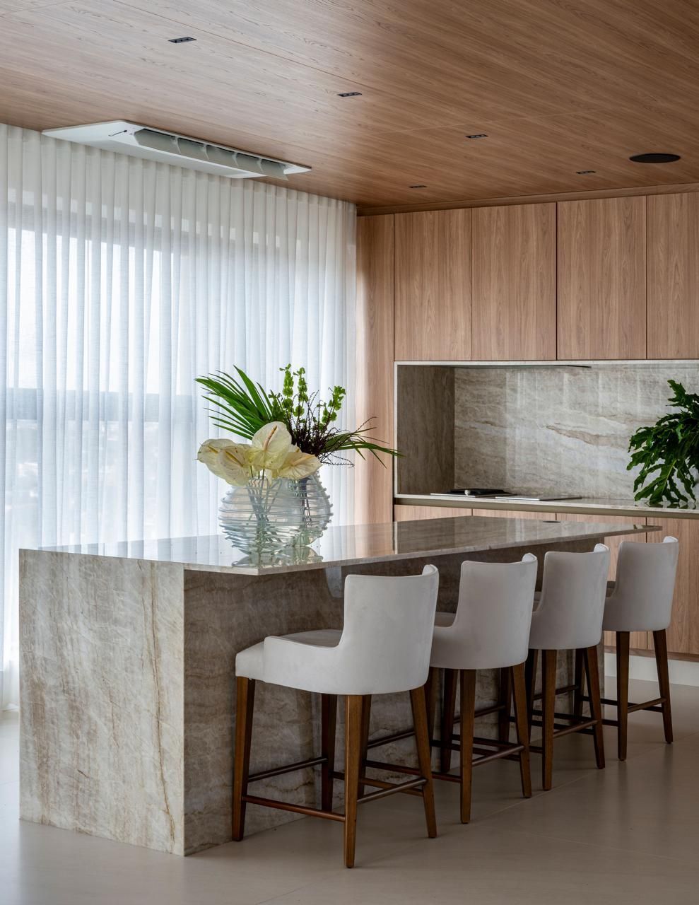 Uma cozinha com uma grande ilha e cadeiras brancas