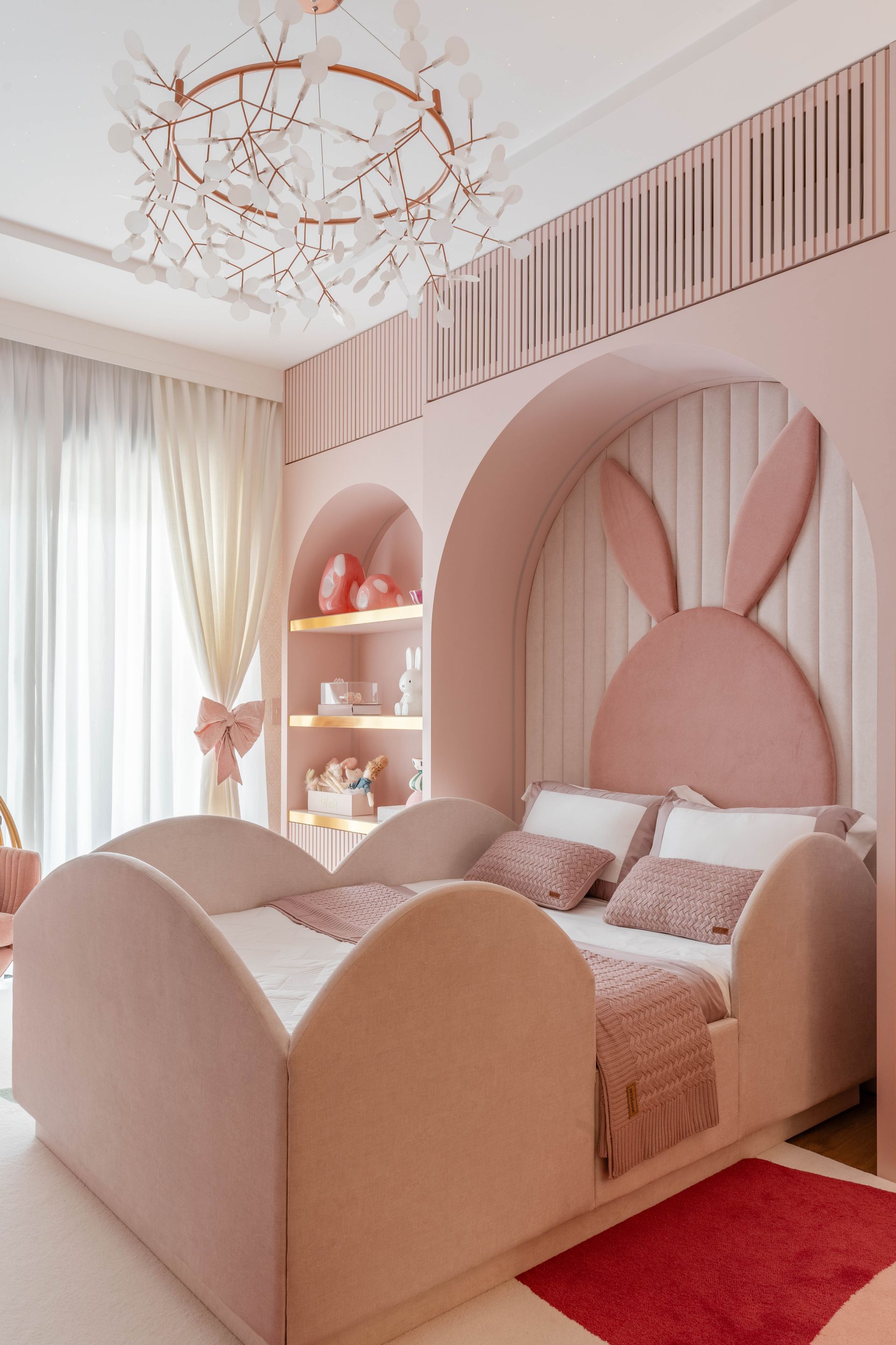 Um quarto rosa com uma cama com orelhas de coelho na cabeceira.