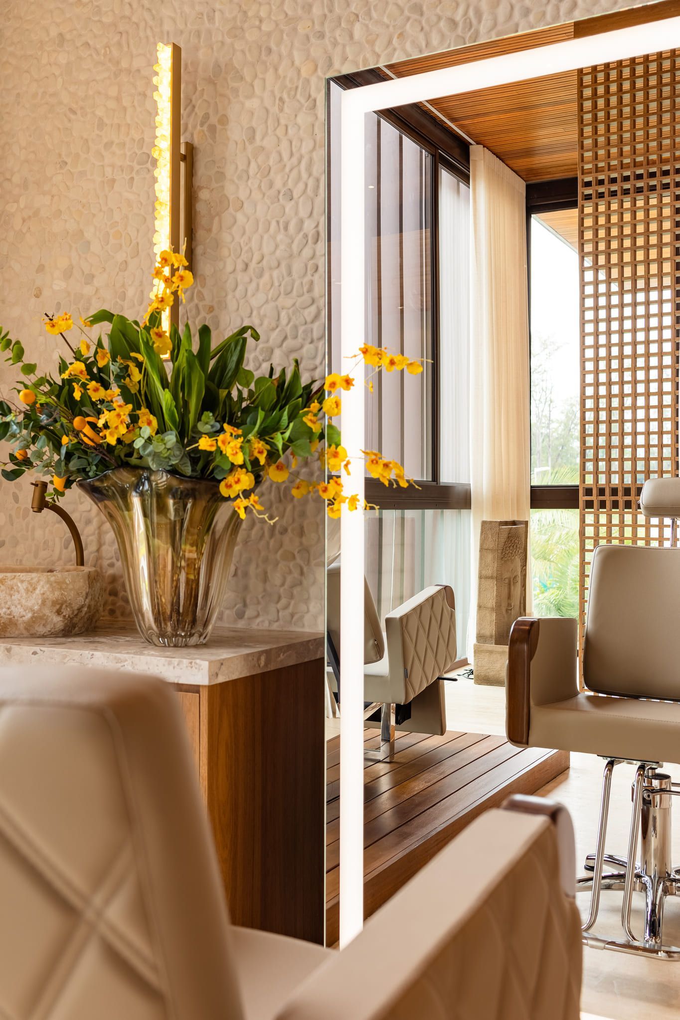 Um salão com um grande espelho e um vaso de flores no balcão.