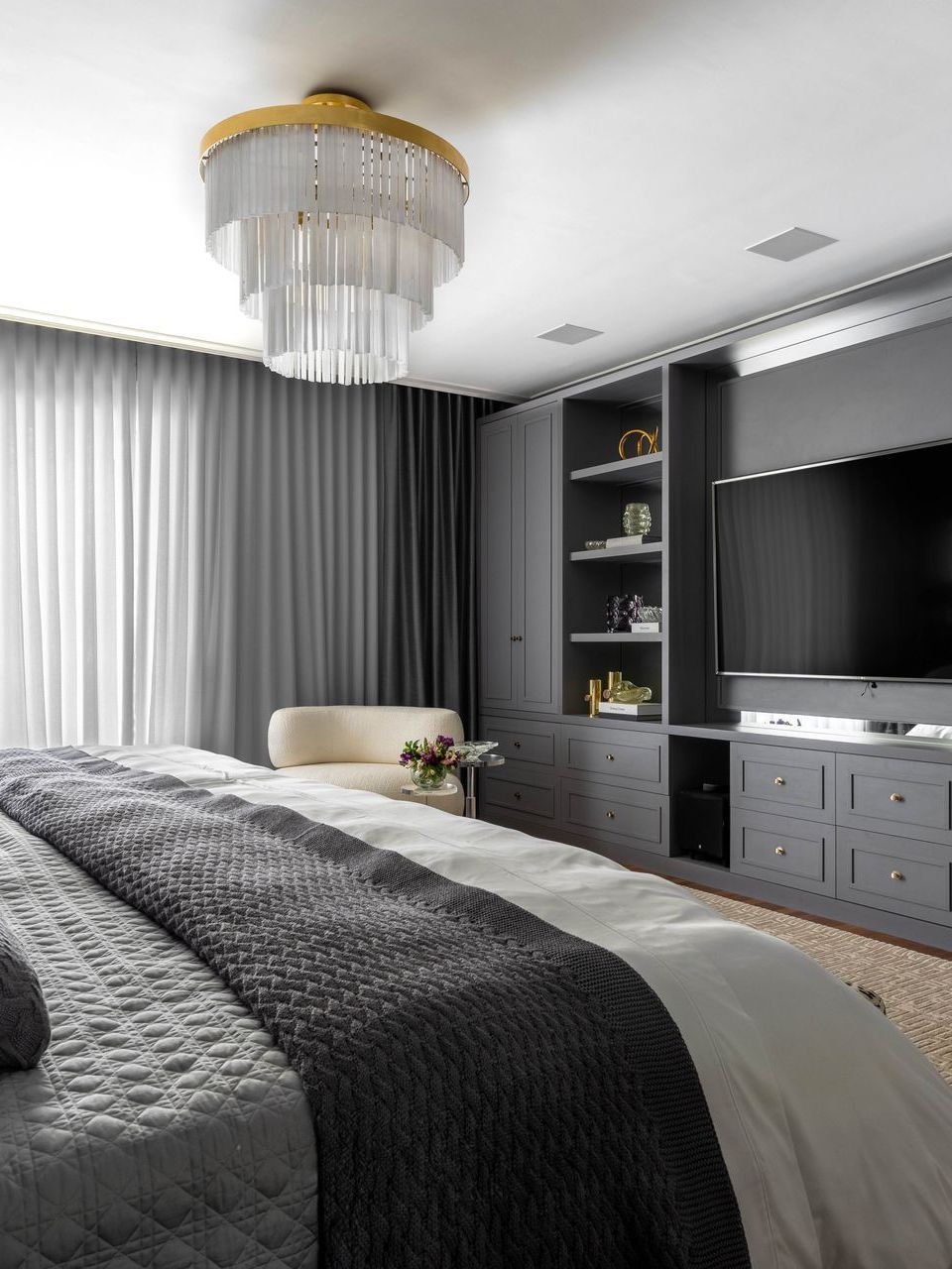 Há uma cama grande no meio do quarto com uma televisão na parede.