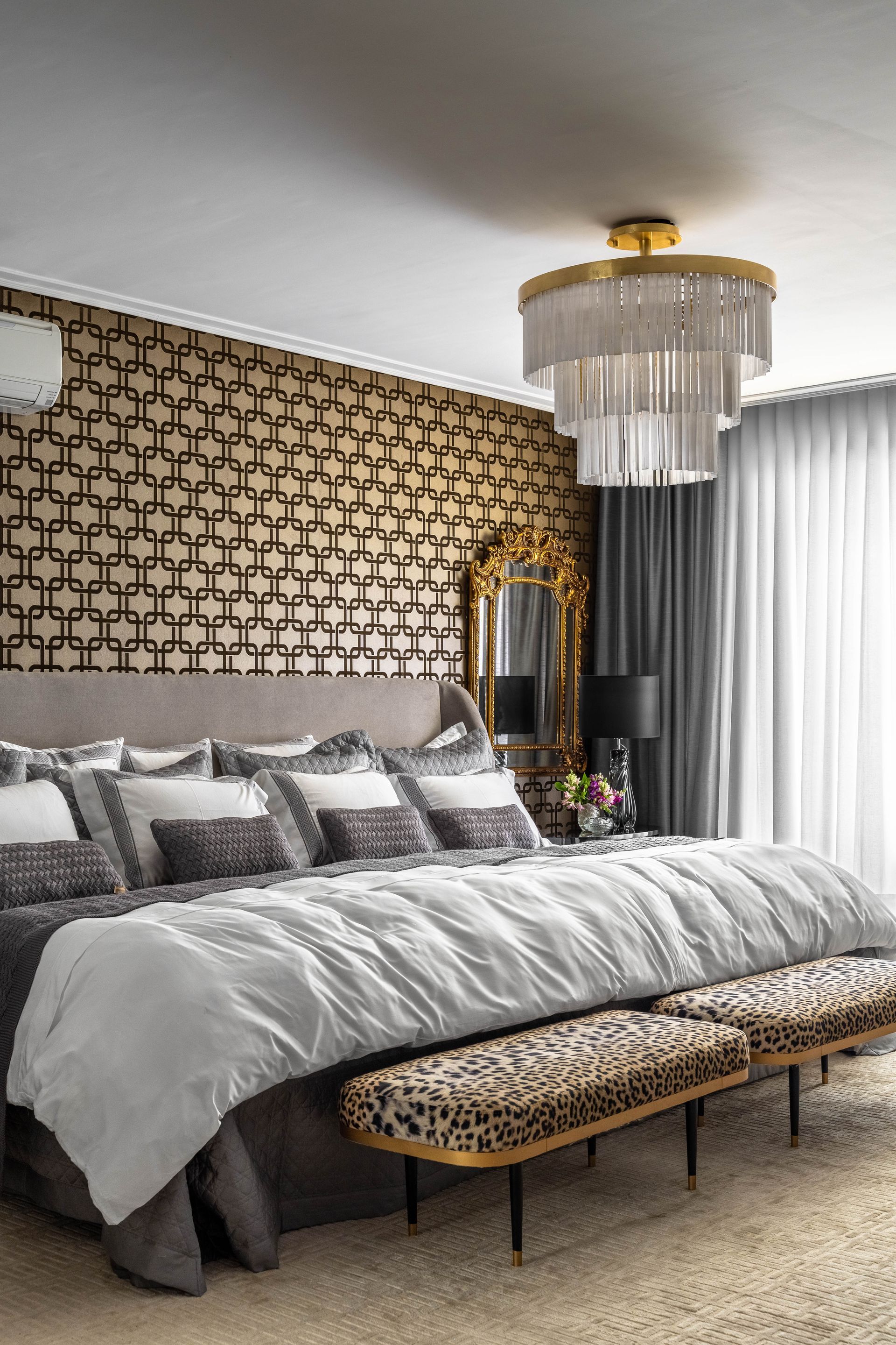 Um quarto com uma cama grande, bancos e um lustre.