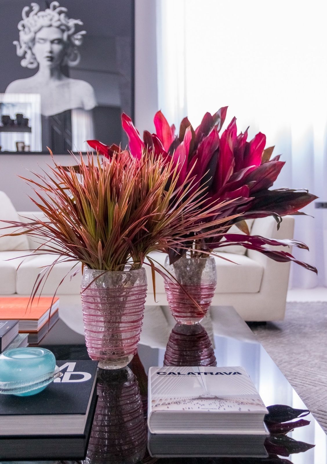 Dois vasos de flores estão sobre uma mesa de centro em uma sala de estar.