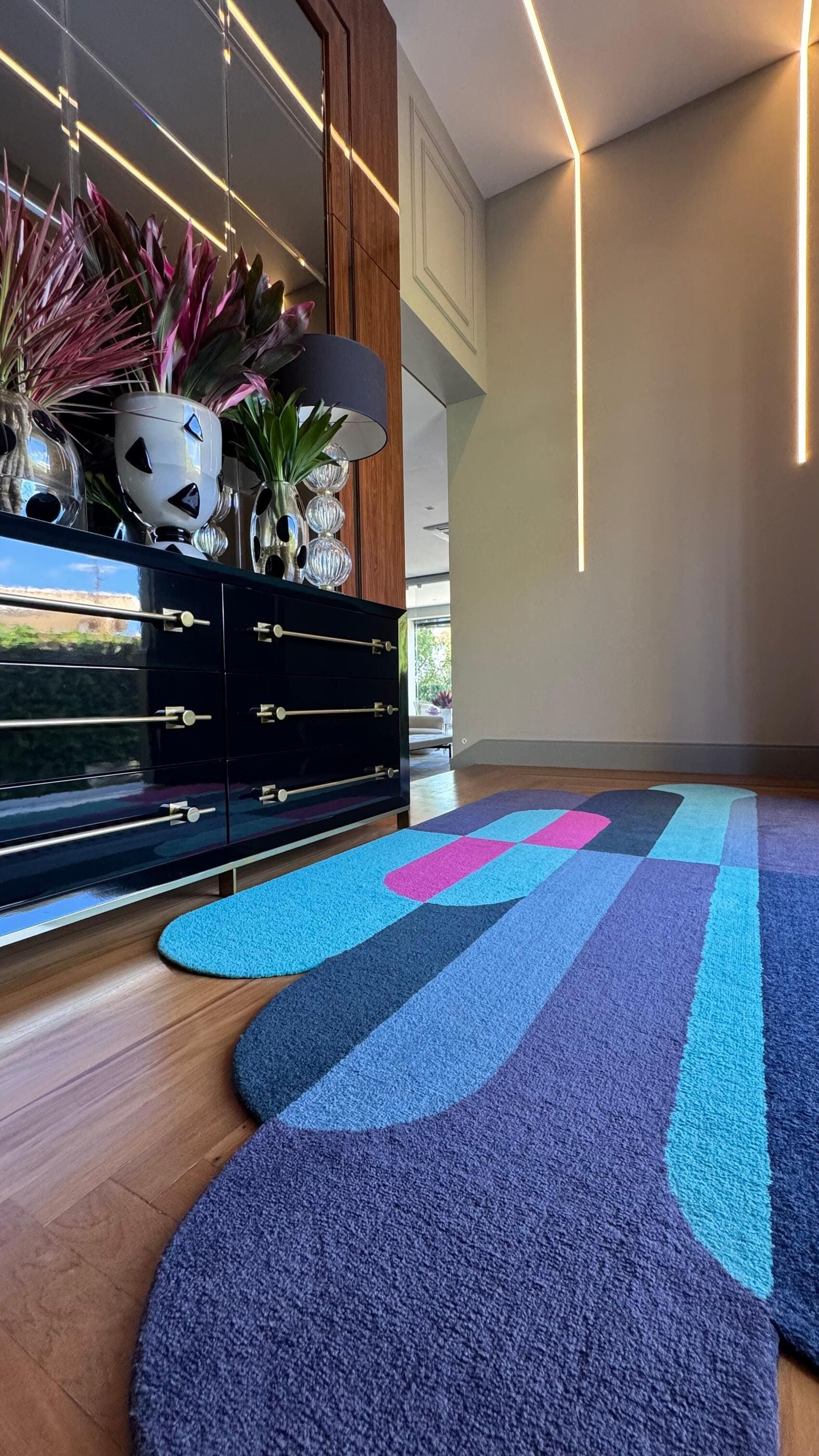 Um tapete colorido está sobre um piso de madeira em uma sala.