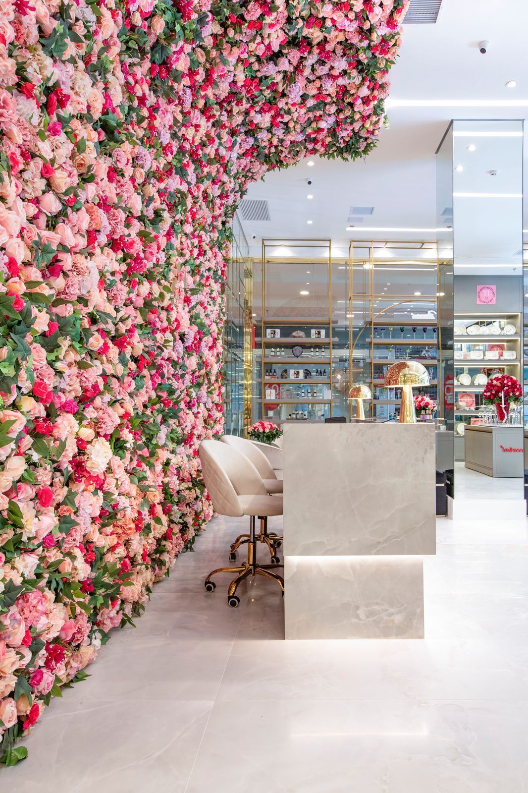 Um balcão de recepção em frente a uma parede de flores rosas.