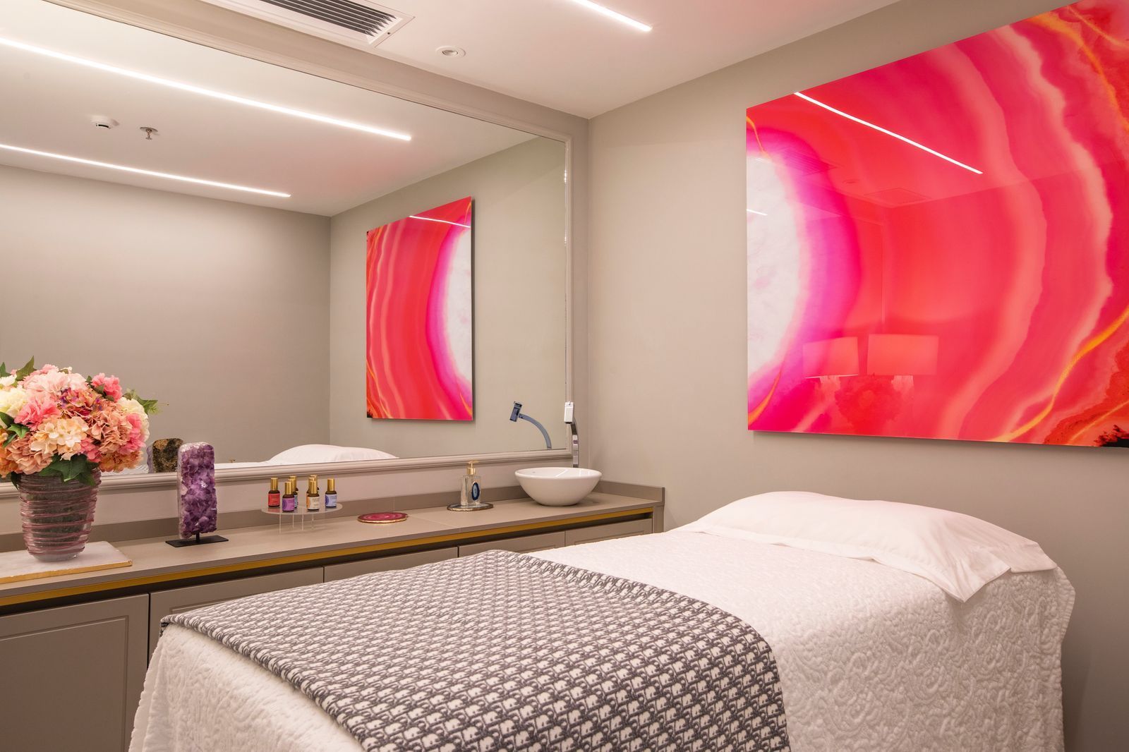 Uma mesa de massagem em uma sala com uma pintura rosa na parede.