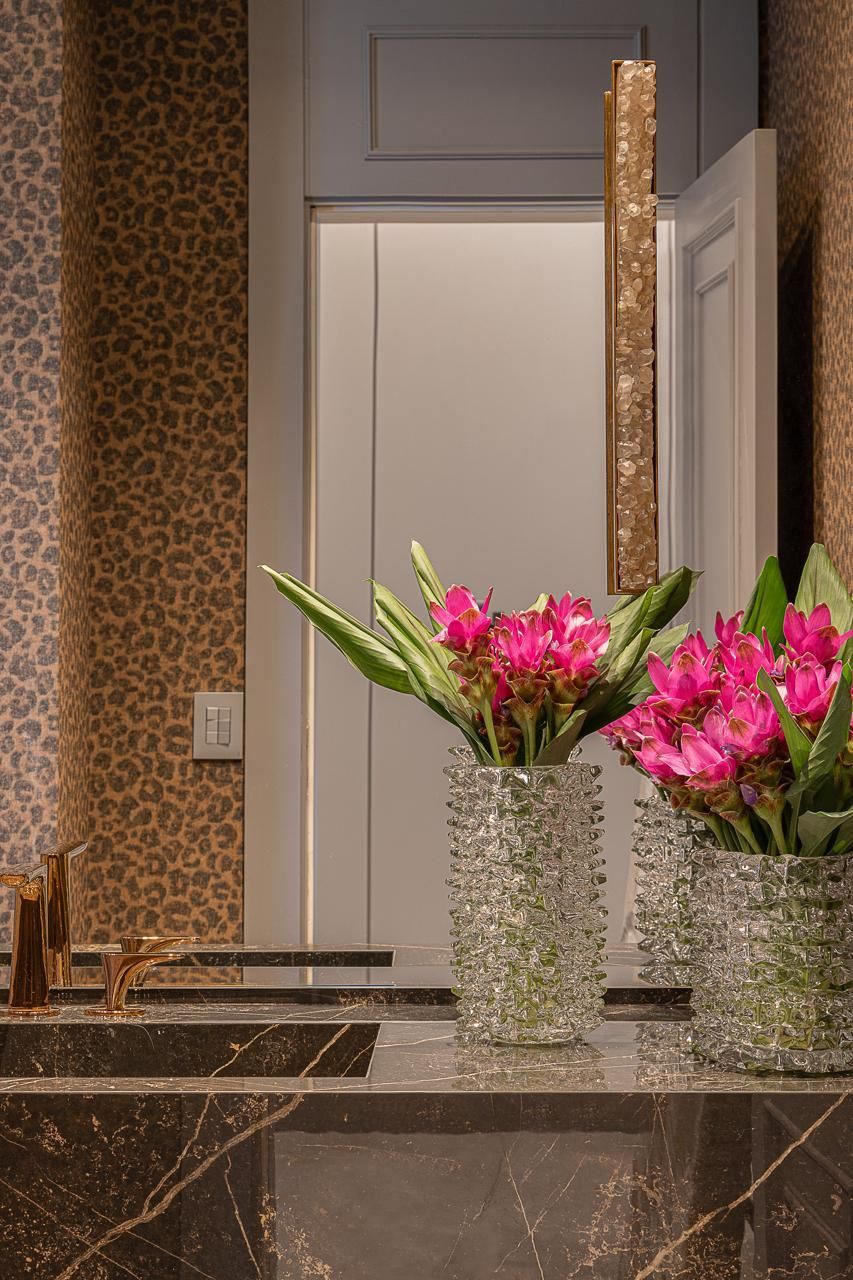Uma pia de banheiro com dois vasos de flores rosas.