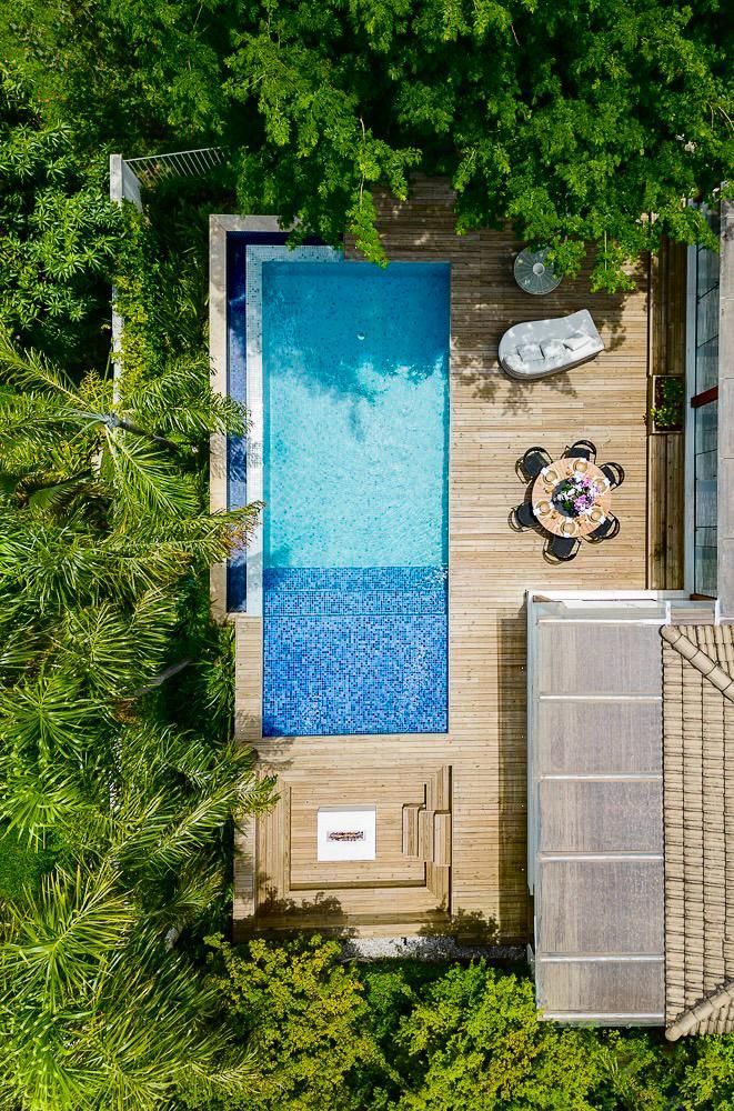 Uma vista aérea de uma piscina cercada por árvores e um deck de madeira.