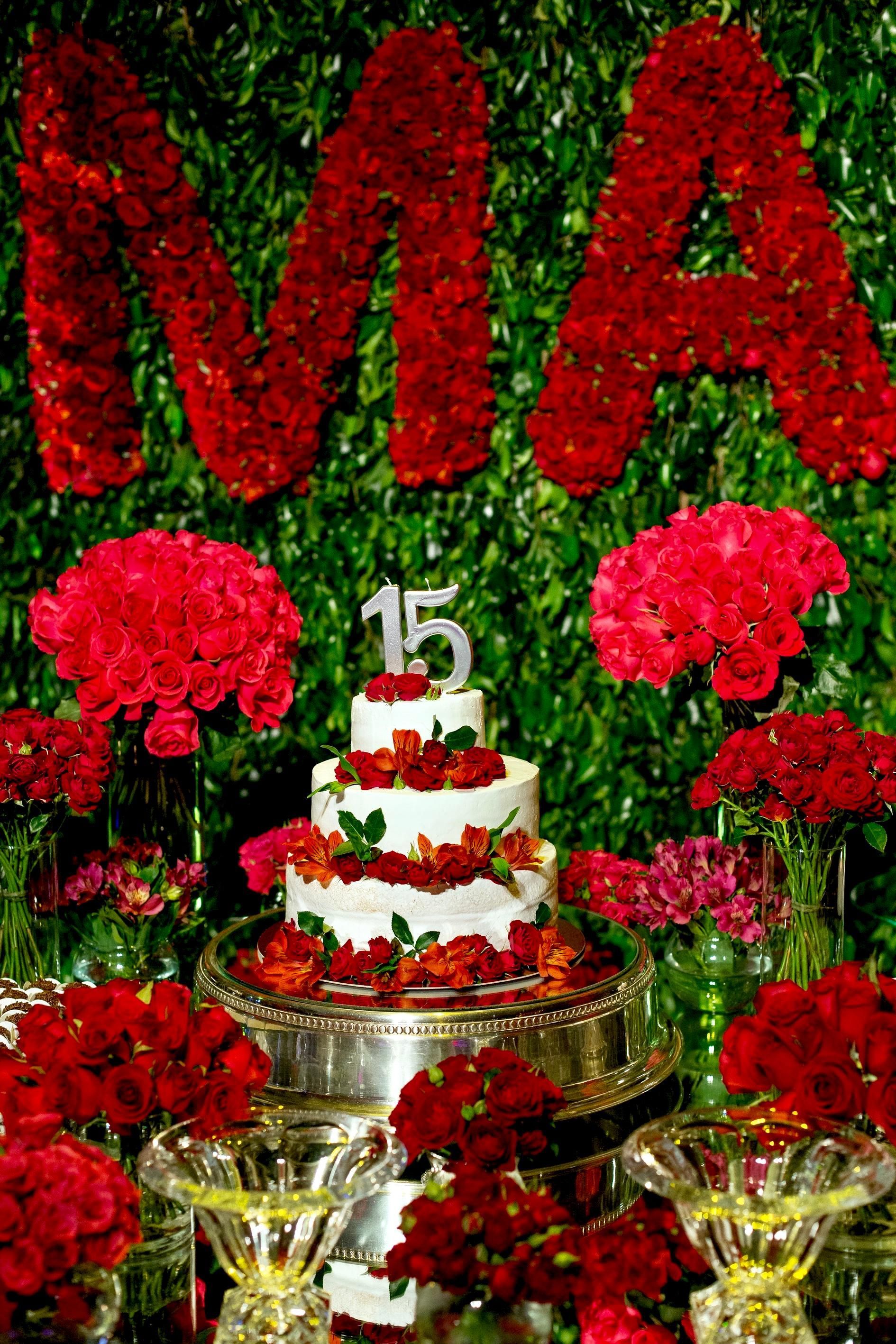 Uma mesa com flores e um bolo com o número 15
