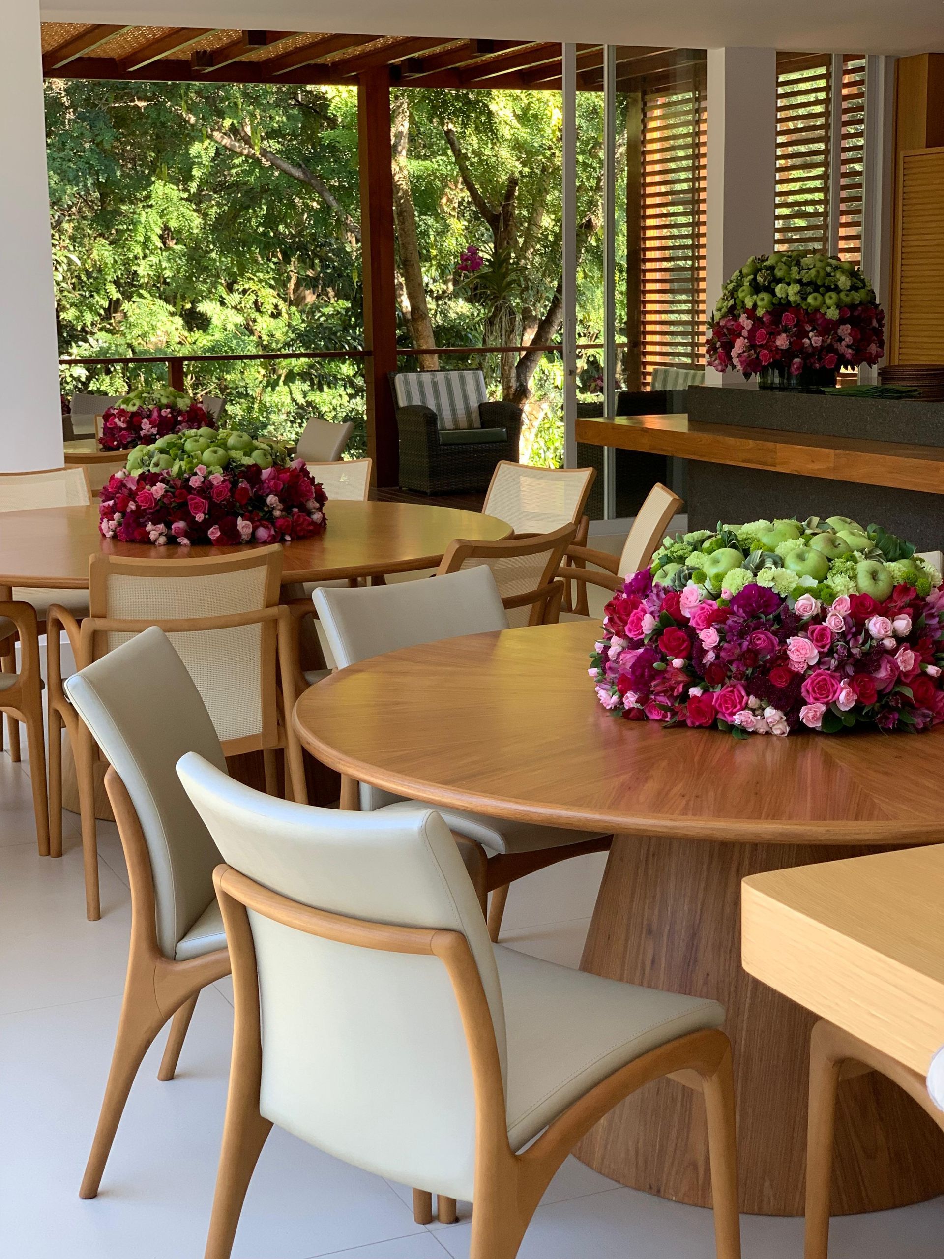 Uma sala de jantar com mesas, cadeiras e flores