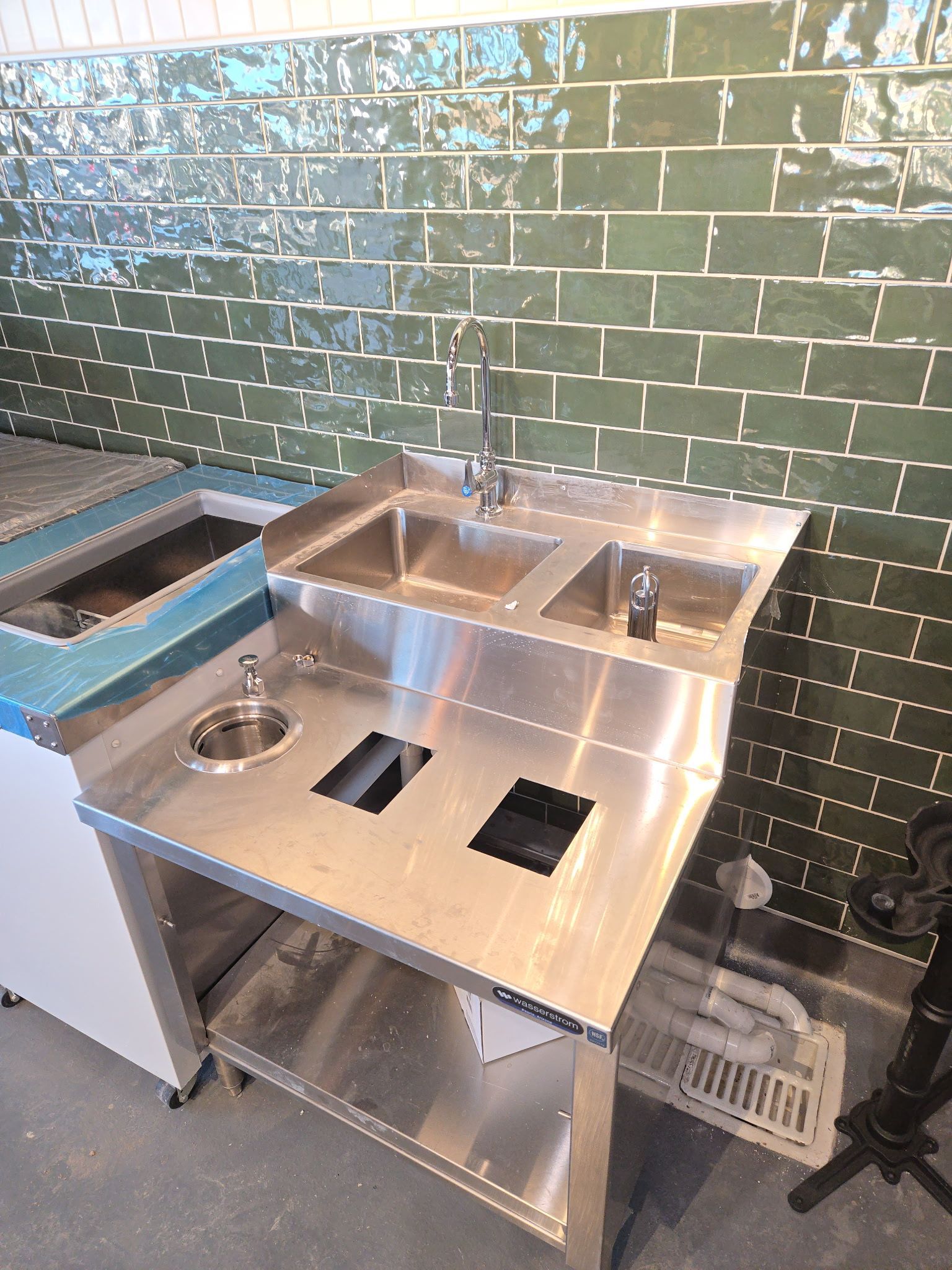 Large family group poses in front of a white brick wall outside. People of varying ages smile and stand together.