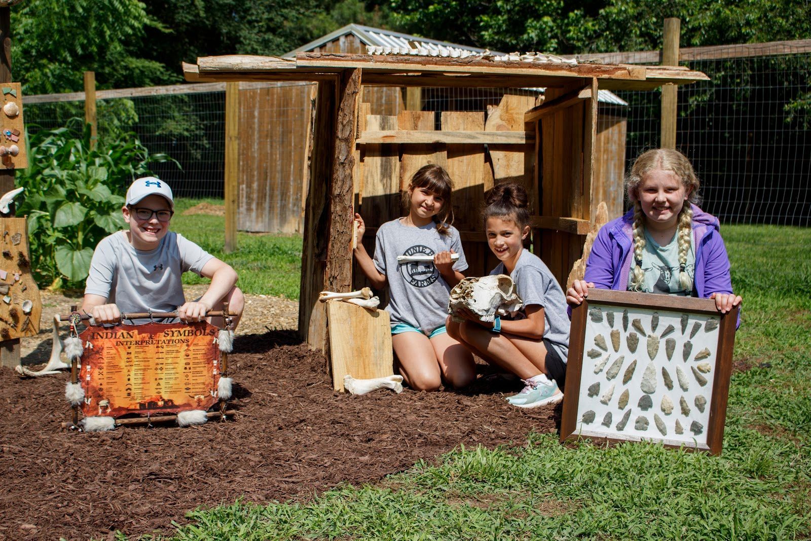 A group of children are posing for a picture in front of a wooden house.