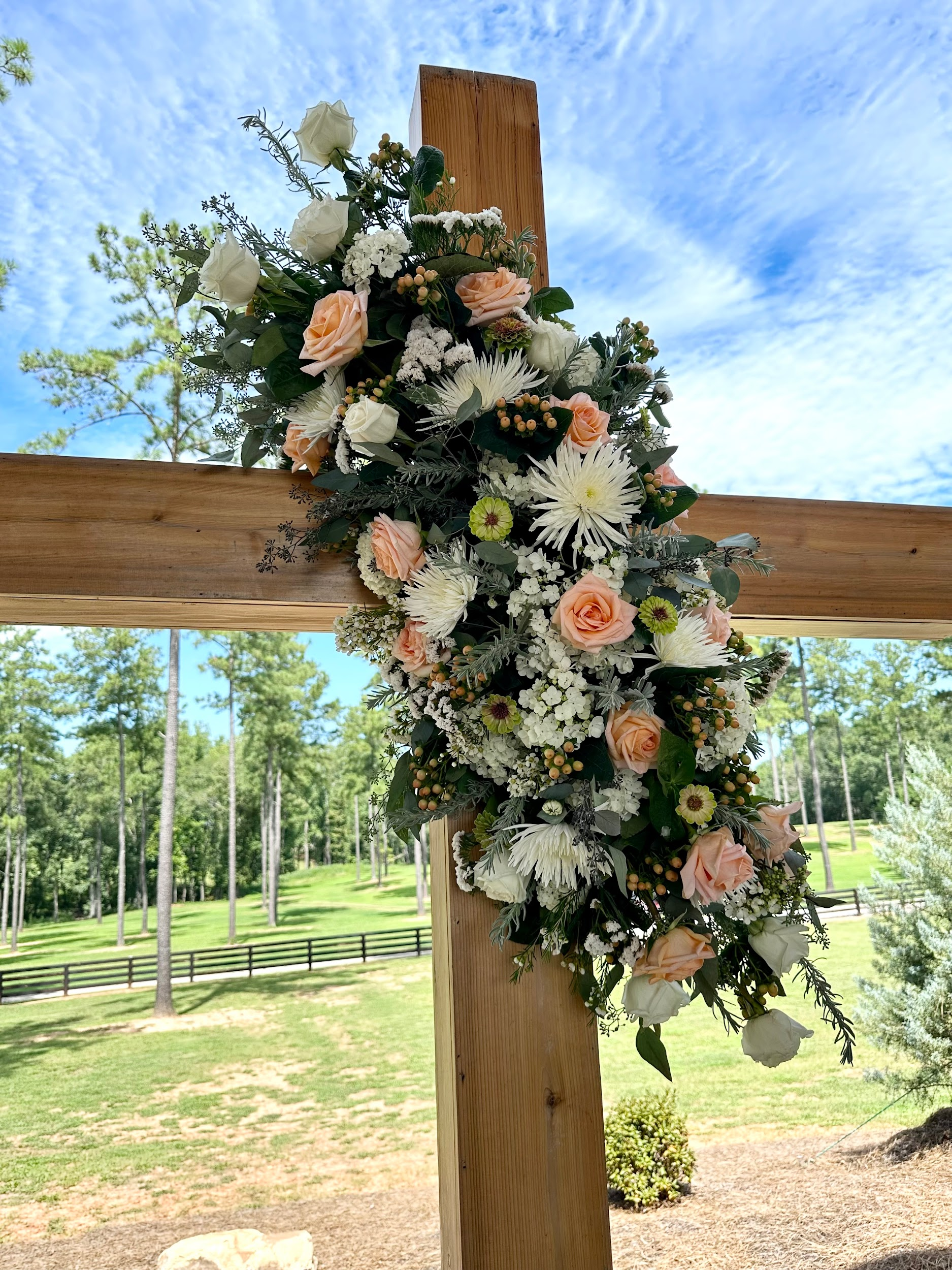 A wooden cross decorated with flowers for a wedding ceremony.