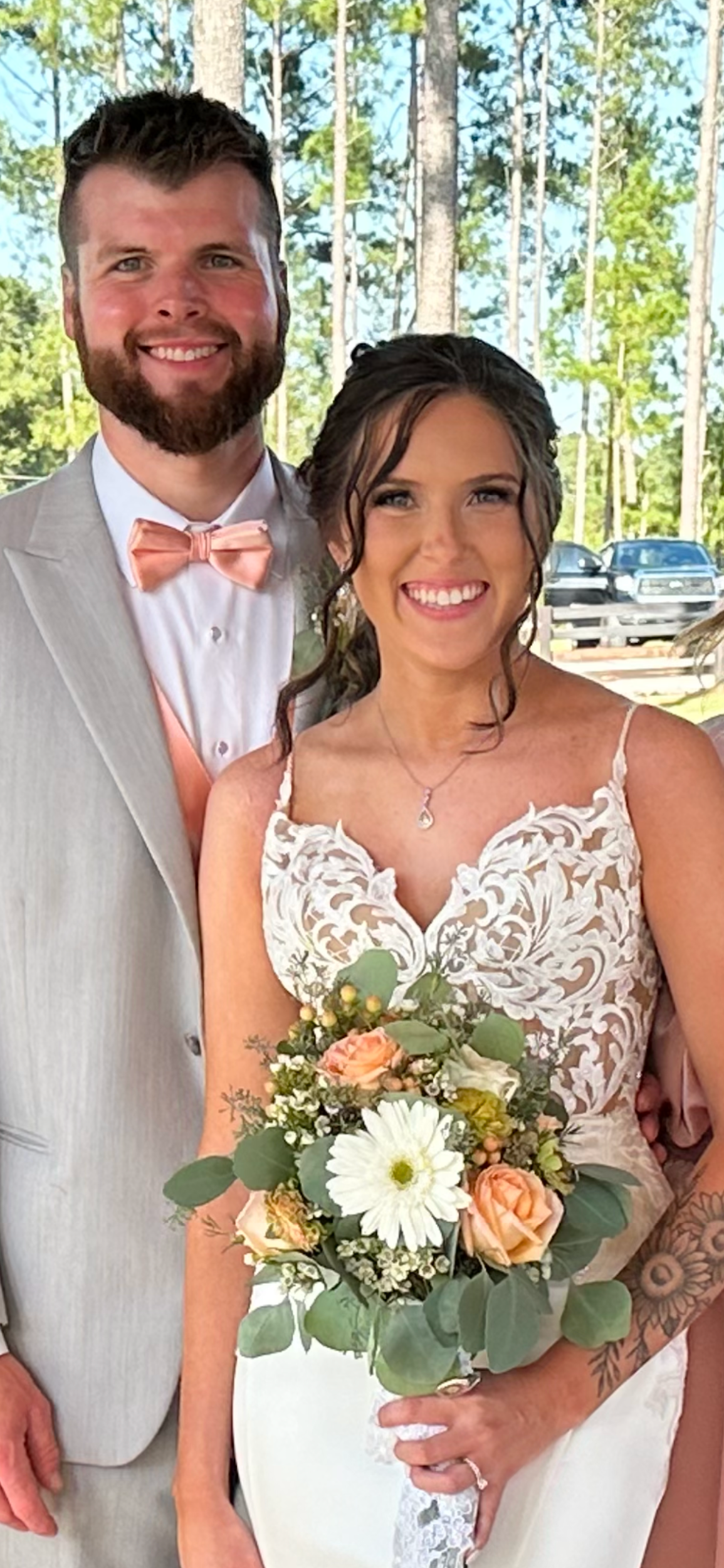 A bride and groom are posing for a picture while the bride is holding a bouquet of flowers.