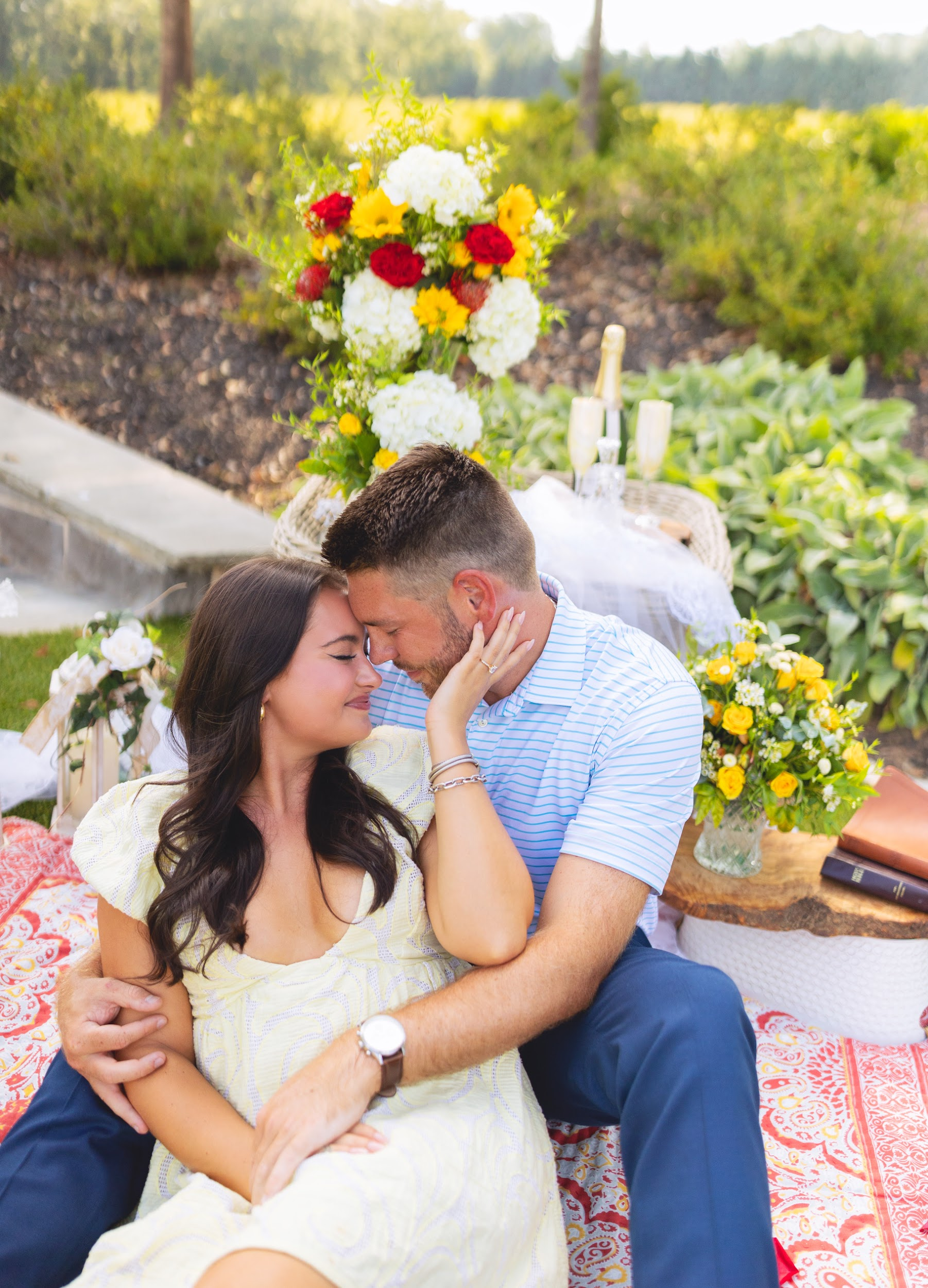 A man and a woman are sitting on a blanket and kissing.